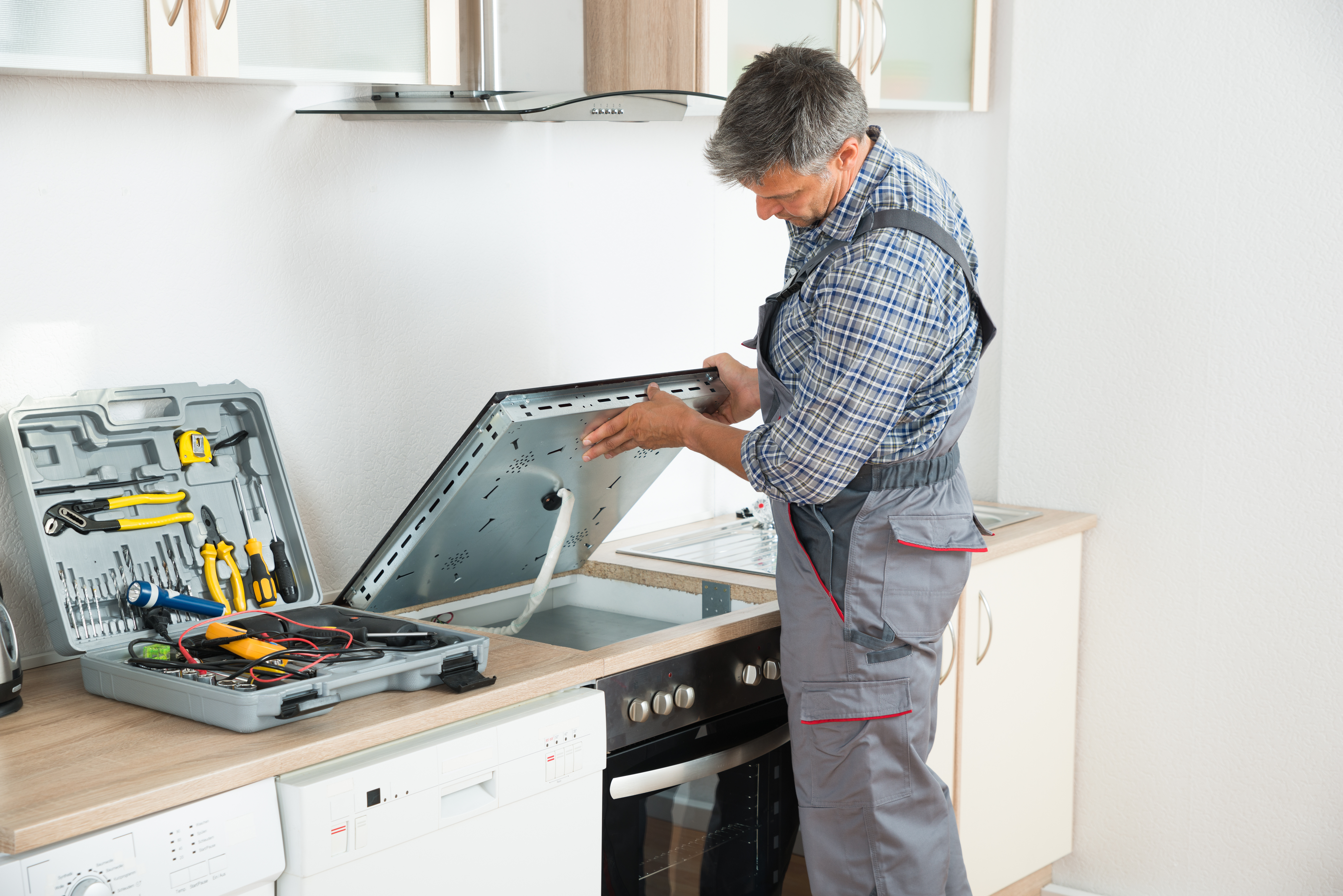 Appliance repair technician in overalls examining a stove