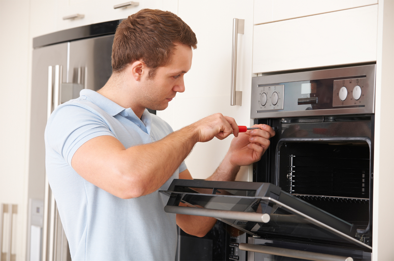 A man in a blue polo shirt fixing an oven